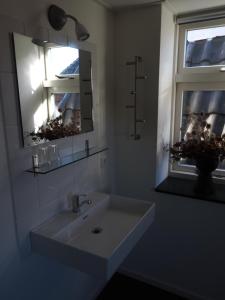 een badkamer met een wastafel, een spiegel en een raam bij Hotel 't Anker in Leeuwarden