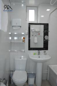 a white bathroom with a toilet and a sink at Nikolyans' Guesthouse in Tsʼoghamarg +35 photos