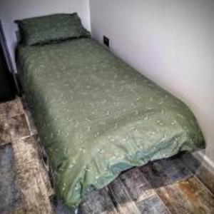 a green bed in a corner of a room at The Orchid in Gillingham