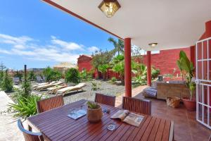an outdoor patio with a wooden table and chairs at Ca'Sita Salobre Pueblo by VillaGranCanaria in San Bartolomé de Tirajana