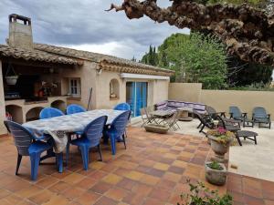 a patio with a table and chairs and a house at La Villa St Antoine in LʼIsle-sur-la-Sorgue