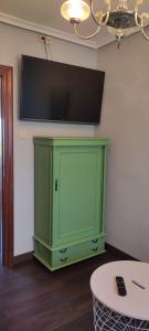 a green cabinet with a flat screen tv on a wall at Apartamento Mirando al Mar in San Juan de la Arena