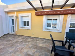 a patio with chairs and a yellow wall and windows at Impresionante Ático en Torre del Mar frente al Mar in Torre del Mar