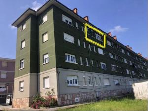 a green building with a yellow sign on it at Apartamento Mirando al Mar in San Juan de la Arena