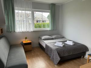 a bedroom with a bed and a couch and a window at DW Róża Wiatrów in Dębki