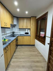 une cuisine avec des armoires en bois, un évier et un micro-ondes dans l'établissement Santa Justa Toledo Centro, à Tolède 2 autres photos