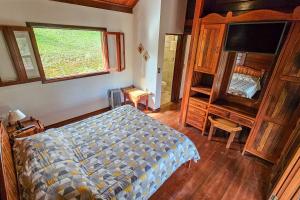 um quarto com uma cama, uma janela e uma televisão em Pousada dos Quatis em Campos de Jordão