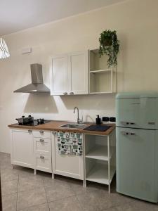 a kitchen with white cabinets and a sink and a refrigerator at A Un Passo Dal Lago in Lesina