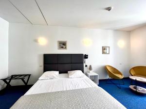 a bedroom with a large bed and two chairs at Le National in S&egrave;te