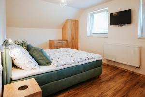 a bedroom with a bed and a tv on the wall at penzion ROSETA in Radějov