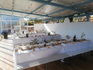 a long table in a room with white tables and wine bottles at Olive Branch El Chorro in El Chorro