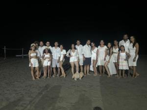 un groupe de personnes debout sur la plage la nuit dans l'établissement Cabaña Villa July, à Moñitos