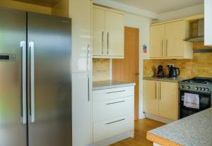 a kitchen with white cabinets and a stainless steel refrigerator at Register House Family or Contractor 4bed with Garden Driveway in Bellshill