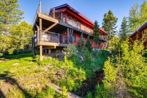 Una gran casa roja con terraza en el bosque. en Hot Tub and Mtn Views Waterfront Grand Lake Cabin!, en Grand Lake
