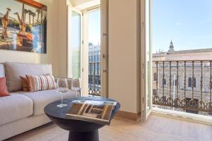 a living room with a couch and a table with wine glasses at Genteel Home San Francisco Suites in Seville