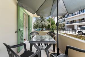 a table and chairs on a balcony with an umbrella at Abatis CityHome in Lefkada