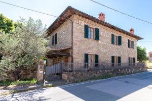 a large stone house with a fence in front of it at La Pineta Farm House in Querce