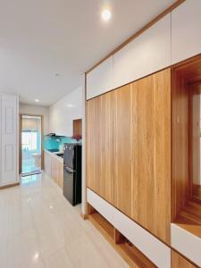 a kitchen with wooden cabinets and a black refrigerator at Dreamy'home-Căn Hộ view biển in Ha Long