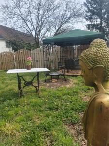 a table and umbrella with a statue in a yard at Pension zum Hollerbusch in Heilbach