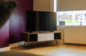 a flat screen tv on a stand in a room at Register House Family or Contractor 4bed with Garden Driveway in Bellshill