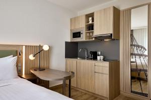 a hotel room with a bed and a desk and a kitchen at Courtyard by Marriott Magdeburg in Barleben