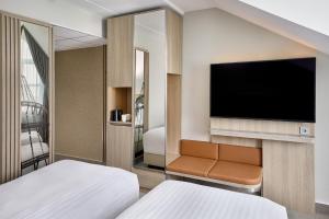 a hotel room with two beds and a flat screen tv at Courtyard by Marriott Magdeburg in Barleben