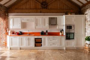 una cocina con armarios blancos y una pared de ladrillo en The Roost, Heritage Escapes, Field House Farm, en Bempton 10 fotos más