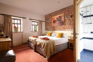 Un dormitorio con dos camas y una pared de ladrillo. en The Roost, Heritage Escapes, Field House Farm, en Bempton