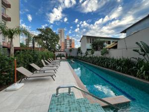 ein Swimmingpool mit Liegestühlen neben einem Gebäude in der Unterkunft Terraço, Aconchegante, Gym, Ar, WiFi, PUCRS, Pet in Porto Alegre