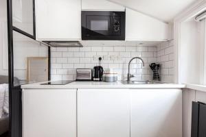a white kitchen with a sink and a microwave at Fabulous Studio in Paddington - 22 in London