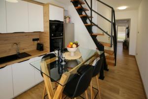 a kitchen with a glass table and chairs and a spiral staircase at Family House Bubalo in Opuzen