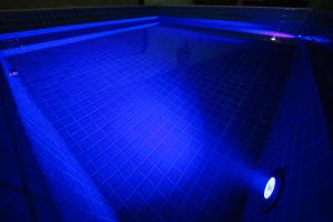 - une piscine avec des lumières bleues dans une pièce sombre dans l'établissement ビーチキャビン - シービュー バーベキュー ピザ サウナ プール ホットタブ - Beach Cabin Chiba - Seaview BBQ Pizza Sauna Pool Hot-tub, à Kobama