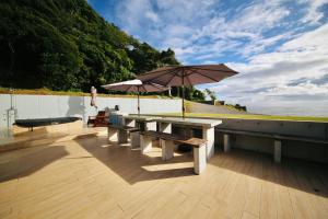 - une table de pique-nique avec un parasol sur une terrasse dans l'établissement ビーチキャビン - シービュー バーベキュー ピザ サウナ プール ホットタブ - Beach Cabin Chiba - Seaview BBQ Pizza Sauna Pool Hot-tub, à Kobama