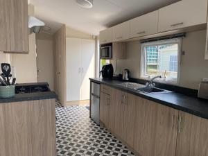 a kitchen with wooden cabinets and a sink and a window at Static Caravan at Lydstep Beach in Tenby
