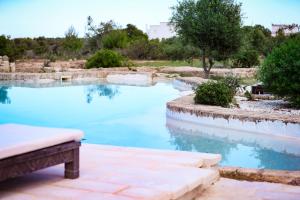 a pool of blue water with a bench and trees at Masseria Piccole Taverne in Rosa Marina
