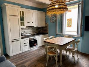 a kitchen with white cabinets and a wooden table with chairs at Appartamento Camillo Benso in Follonica
