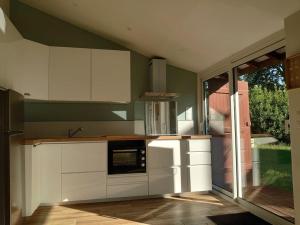 a kitchen with green walls and white cabinets at Logement Nature Plages Forêts in Lévignacq