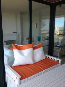 łóżko z pomarańczowymi i białymi poduszkami w pokoju w obiekcie Apartment Outeiro da Vela w mieście Cascais