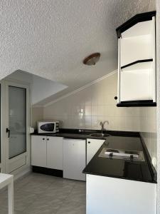 a kitchen with white cabinets and a black counter top at Hotel Meve Mar in Somo