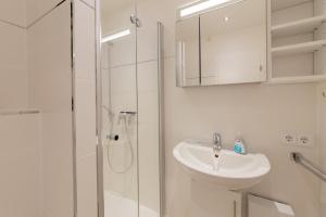 a white bathroom with a sink and a shower at Ferienwohnung Ankommen in Timmendorfer Strand +30 photos
