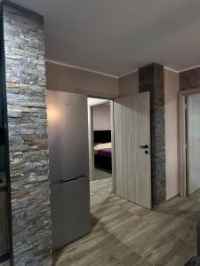 ein Wohnzimmer mit Steinmauer und Kühlschrank in der Unterkunft Apartman Dašić in Jagodina