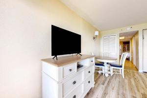uma televisão de ecrã plano numa cómoda branca num quarto em Compass Cove 655 em Myrtle Beach