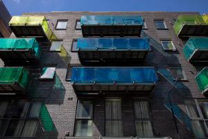 ロンドンにあるBob W Tower Hill Residencesの青と緑のバルコニーが付いた高いレンガ造りの建物