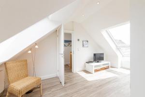 a white living room with a tv and a chair at Ferienwohnung 2 Haus Meeresrauschen in Haffkrug