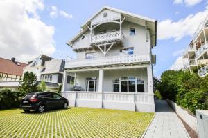 a car parked in front of a white house at Ferienwohnung Long Island in Travemünde