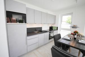 a kitchen with white cabinets and a dining table at Ferienwohnung Küstentraum 2 in Travemünde