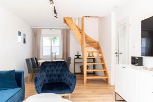 a living room with a blue chair and a staircase at Ferienhaus Das Kleine Strandhaus Scharbeutz in Scharbeutz