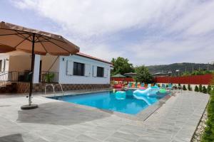 ein Swimmingpool mit Sonnenschirm neben einem Haus in der Unterkunft Villa Valentino Swimming Pool in Moravë