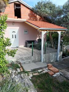 a small pink house with a porch and a white door at Oaza in Komarna