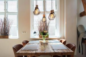 une salle à manger avec une table en bois et des lampes suspendues dans l'établissement Ferienwohnung Nordic Nature Loft in Travemünde direkt in der Vorderreihe inkl Privatsauna, à Travemünde 33 autres photos